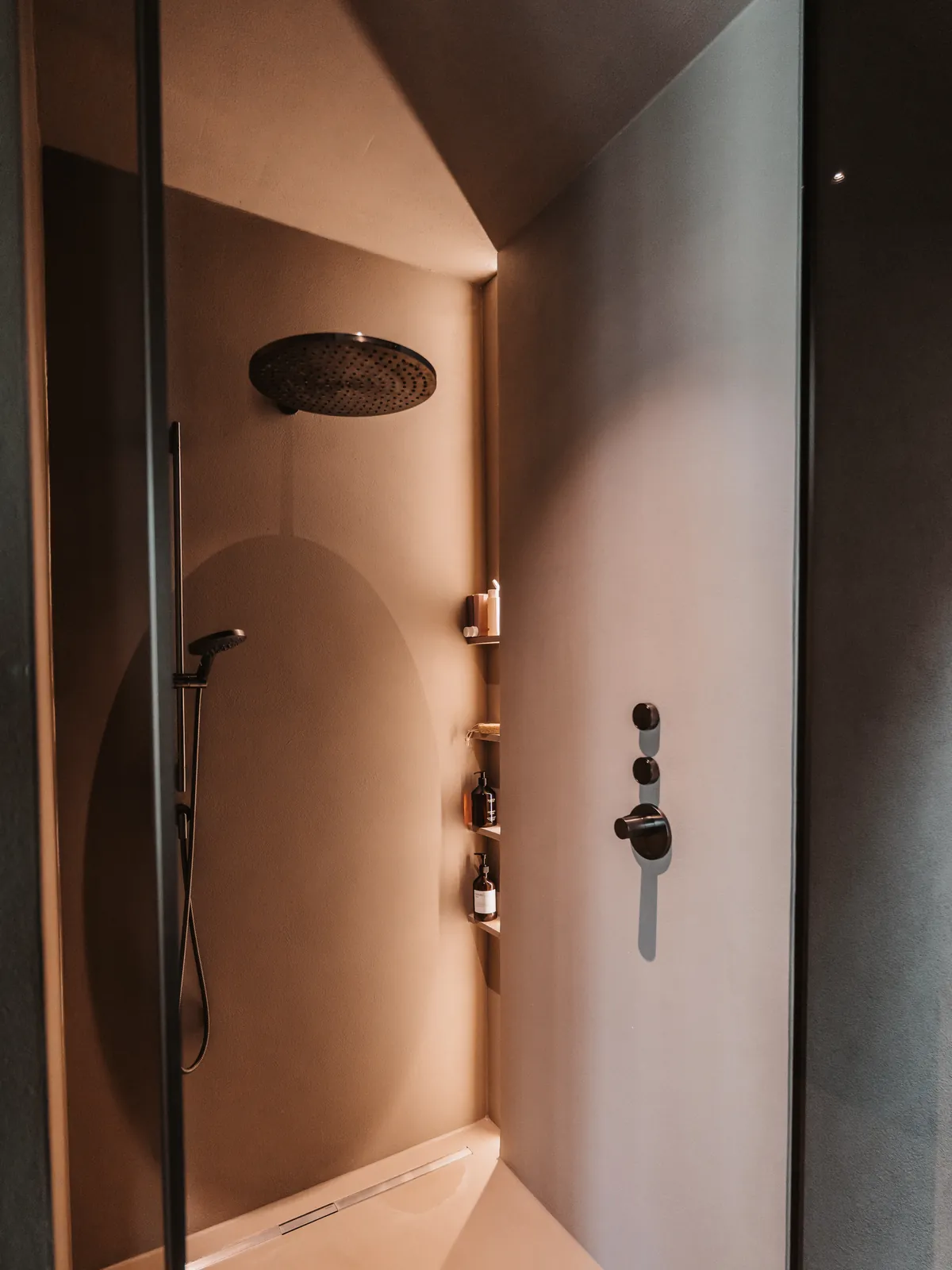 Gerundete fugenlose Dusche in warmem Ton mit Regendusche