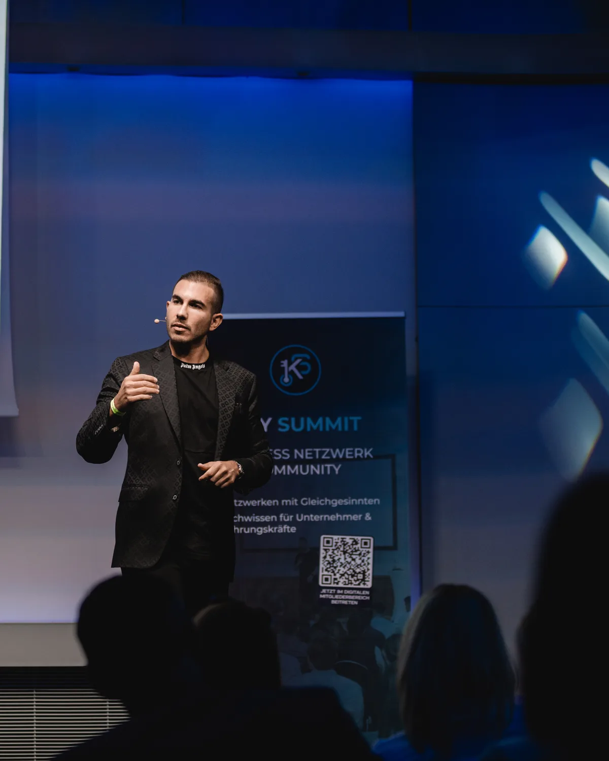 Samy El Makarem auf der Bühne des Key Summit, hinter ihm das Roll-up der Veranstaltung, im Vordergrund das Publikum.